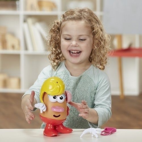 A little one having fun inserting parts into the Mrs. Potato Head toy.