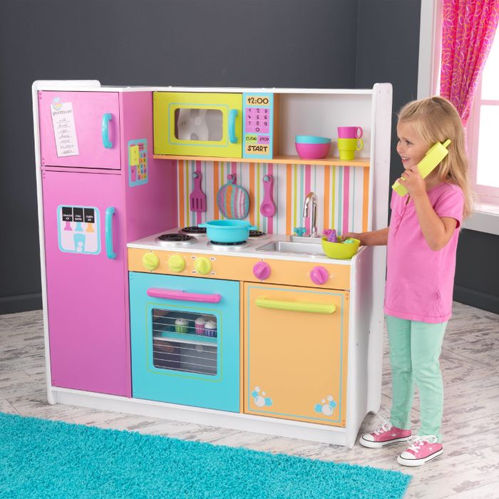 A little one happily playing with a colorful child-sized kitchen set.