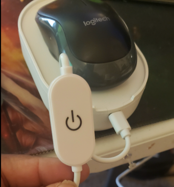 A reviewer demonstrating the power button on the device