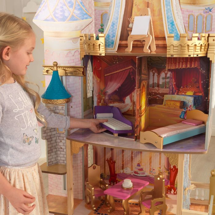 a child placing a piece of furniture into a Disney Princess castle