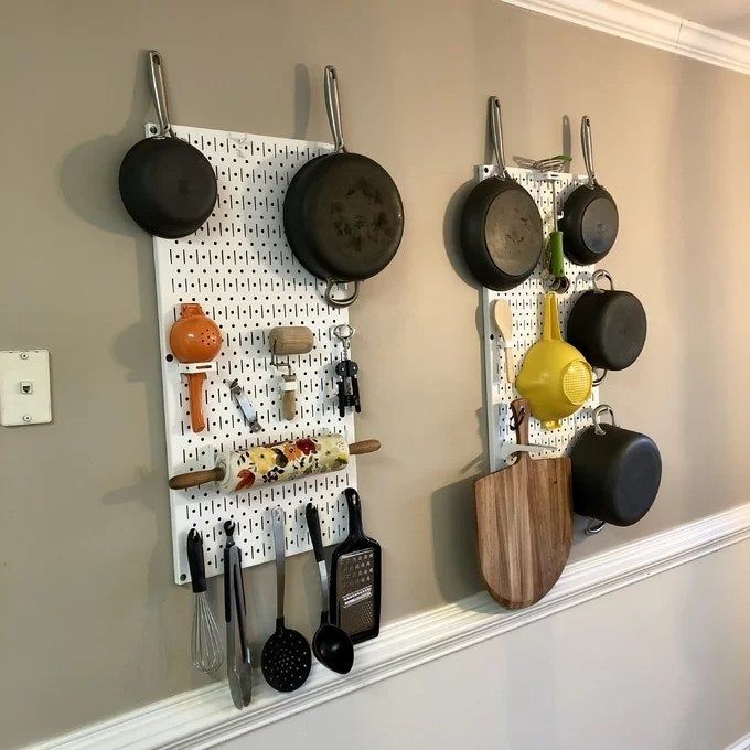 A photo from a reviewer showcasing the White pegboards being used to organize pots, pans, and various kitchen tools.