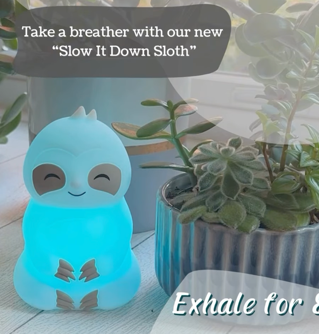 A glowing sloth nightlight surrounded by potted plants with the text: