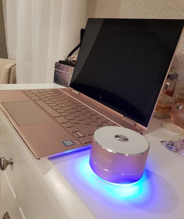 A reviewer displaying the compact circular speaker next to a laptop.