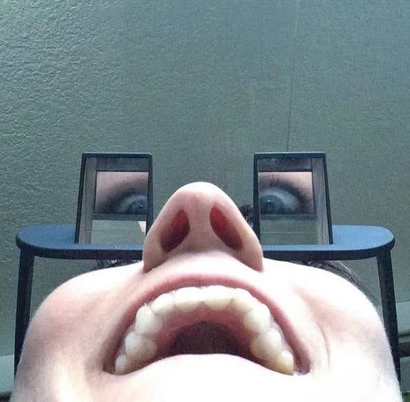 A reviewer wearing the glasses and taking a playful selfie, showing their eyes reflected in the prism mirrors