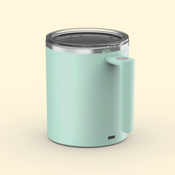 A soft green mug with a handle and a shiny stainless steel rim.