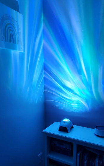 A projector displaying blue dynamic wave patterns on a wall.