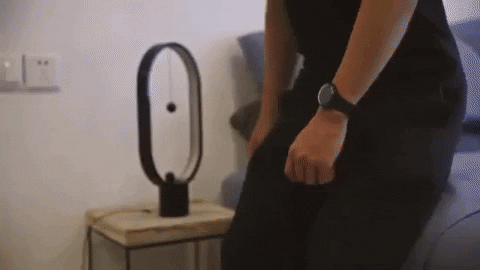A person is using strings to connect two magnetic balls in order to activate a lamp.