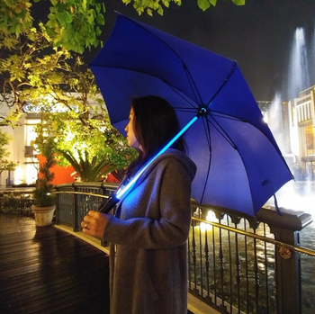 A reviewer demonstrating the umbrella in blue, with a glowing shaft that resembles a lightsaber.