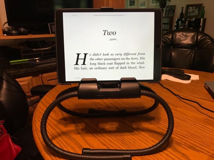 The stand with its legs folded beneath it, resting on a tabletop and supporting a tablet.