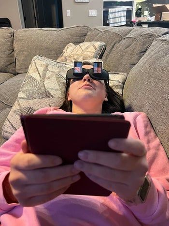 A reviewer using the glasses to read on their Kindle