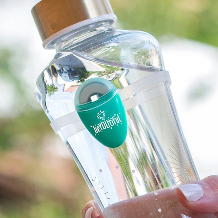 The teardrop-shaped hydration tracker clipped onto a silicone band, which is then secured to a glass water bottle.