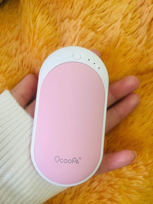 A reviewer holding the hand warmer in a pink color.