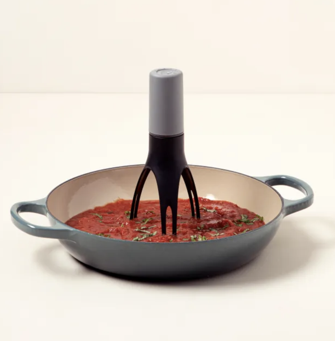 The pan stirrer placed in a pan filled with simmering sauce.