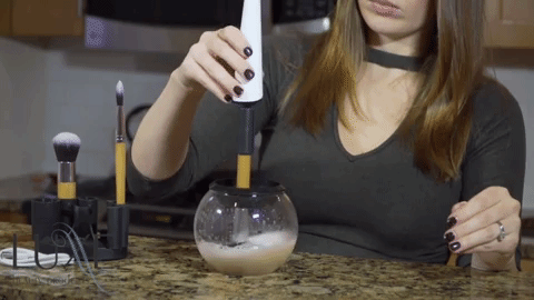 A GIF showing a model using the brush cleaner.