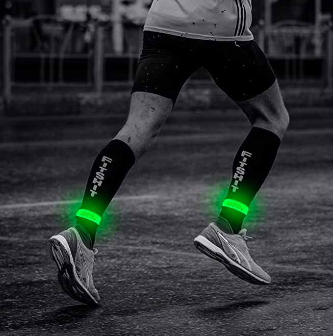 The model wears green glow-in-the-dark bands around their ankles as they run through the night, staying visible even in the dark.