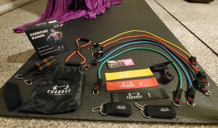 Reviewer displays the full set of resistance bands and additional workout gear neatly arranged on a yoga mat.