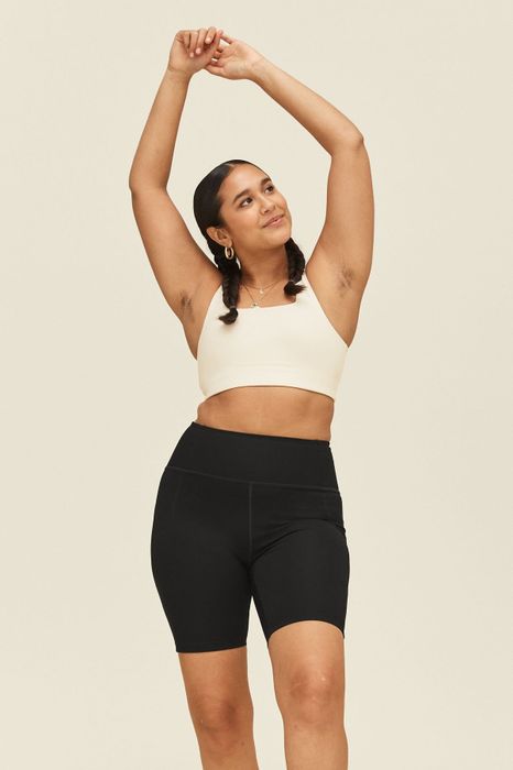 The model is seen wearing black bike shorts paired with a white sports bra, ideal for both style and comfort during physical activities.