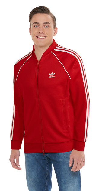 The model is wearing a red Adidas track jacket paired with jeans.