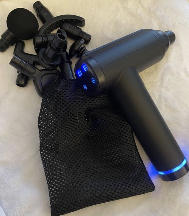 A massage gun placed next to its interchangeable head attachments, ready for use in muscle recovery.