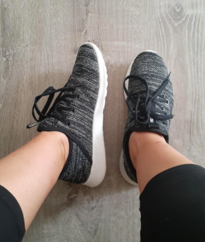 Reviewer wears the same gray Adidas running shoes while resting their feet on a hardwood floor.