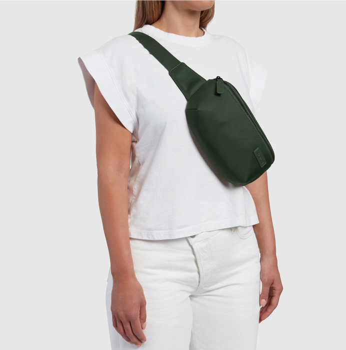 A model sports a green nylon fanny pack, worn across their torso for a practical, on-the-go accessory.