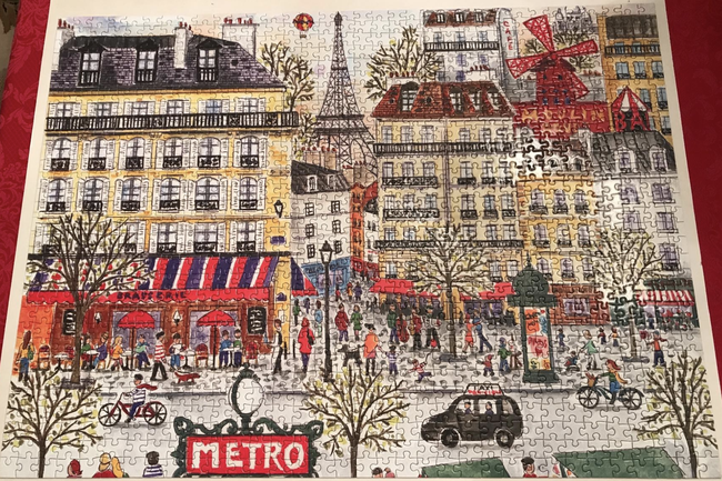 A reviewer proudly displaying their completed puzzle of a Parisian scene