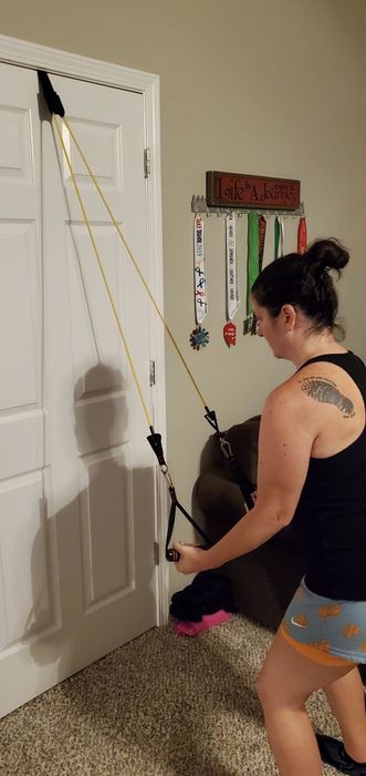 Reviewer demonstrates using the yellow resistance bands for triceps exercises, attached to a doorway for extra support.