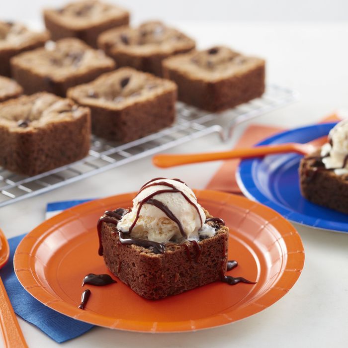 Brownies cooling on a rack, with one topped with a scoop of ice cream.
