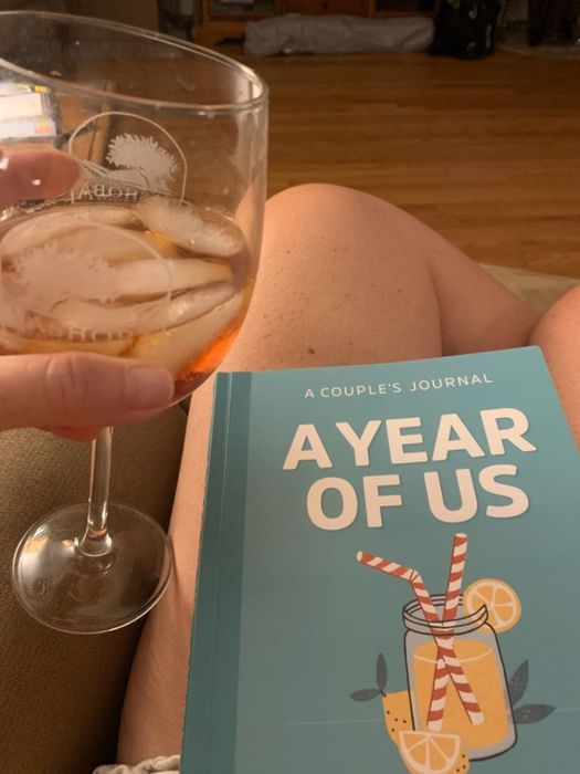 A reviewer sitting with the book in their lap, holding a drink