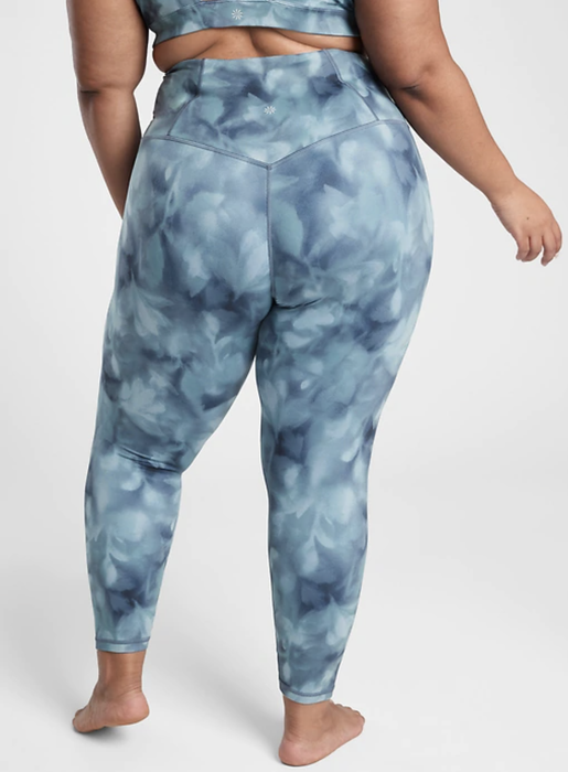The model sports blue tie-dye leggings paired with a matching bra, creating a vibrant and coordinated look.