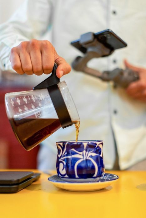 A person pours coffee into a blue and white mug.