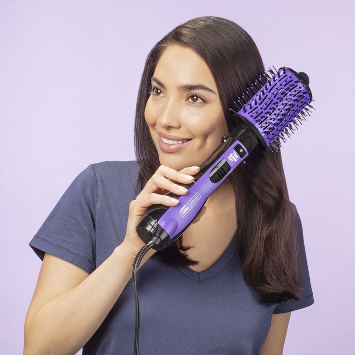A person is using a purple hot air brush to style their hair.