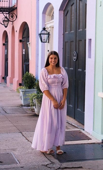 A reviewer wearing a lilac-colored dress.