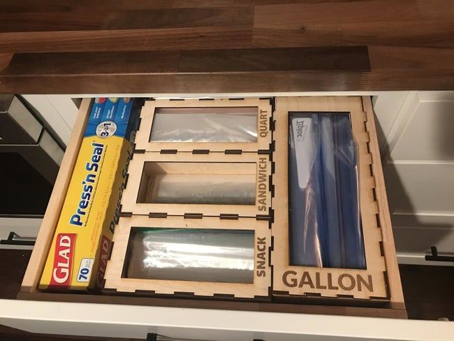 A kitchen drawer neatly organized with sections to hold different sizes of plastic bags.