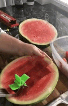A gif showing a reviewer easily using the cutter to slice half a watermelon