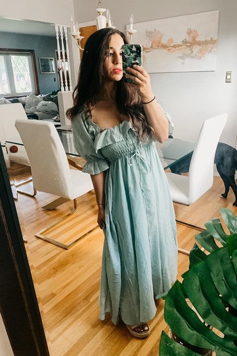 A reviewer in a mint green ruffled short-sleeve dress.