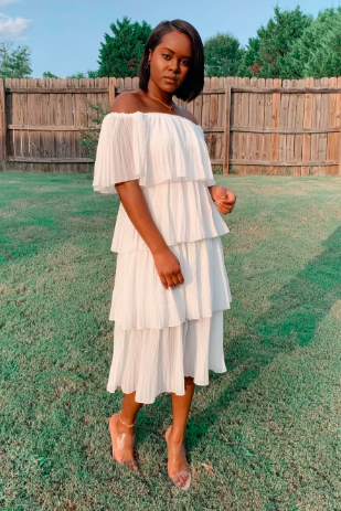 A reviewer dons a white dress in this image.