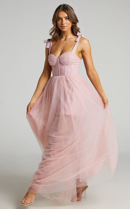 A model sporting a chic pink tulle dress with a flattering bustier top.
