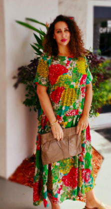 A reviewer wearing a t-shirt dress featuring a vibrant jungle pattern in green, red, and yellow.