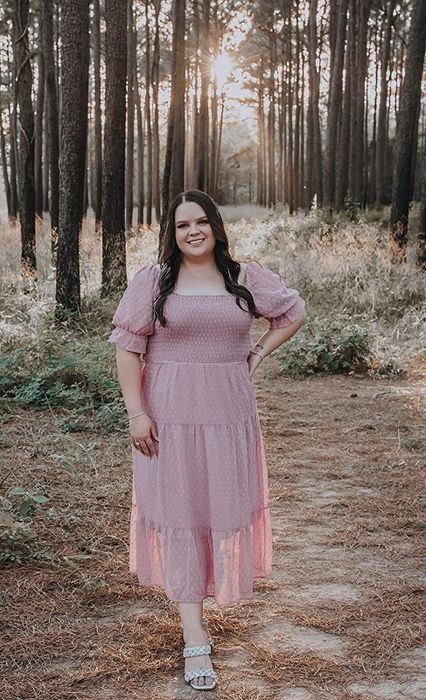 Reviewer wearing a pink ruffled dress in a forest