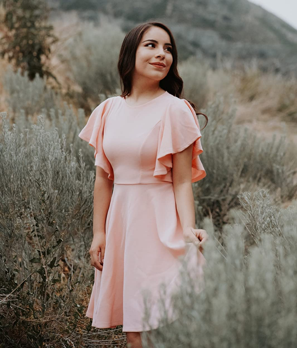 A reviewer in a soft light pink dress.
