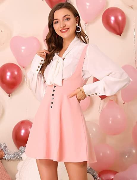 A model styled in a soft pink pinafore dress with suspenders.
