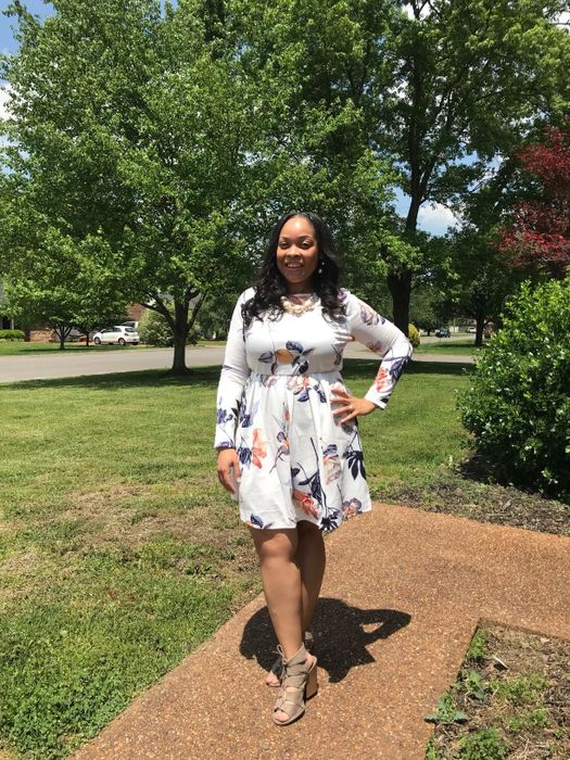 A reviewer is shown wearing a white dress with floral prints.