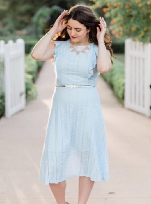 A reviewer is shown in a light blue dress.