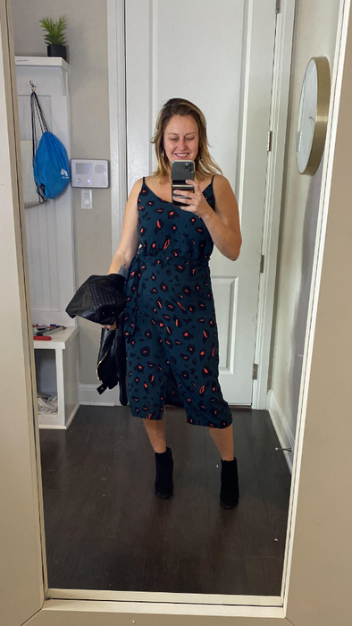 A reviewer rocking the dress with ankle boots while holding a jacket, showing off the perfect pairing.