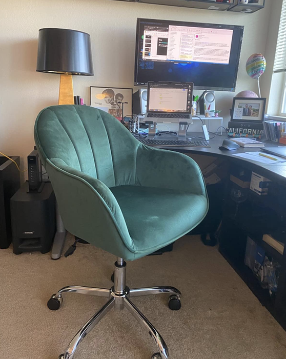 A reviewer image showing a green velvet swivel armchair with thin armrests in front of a desk.