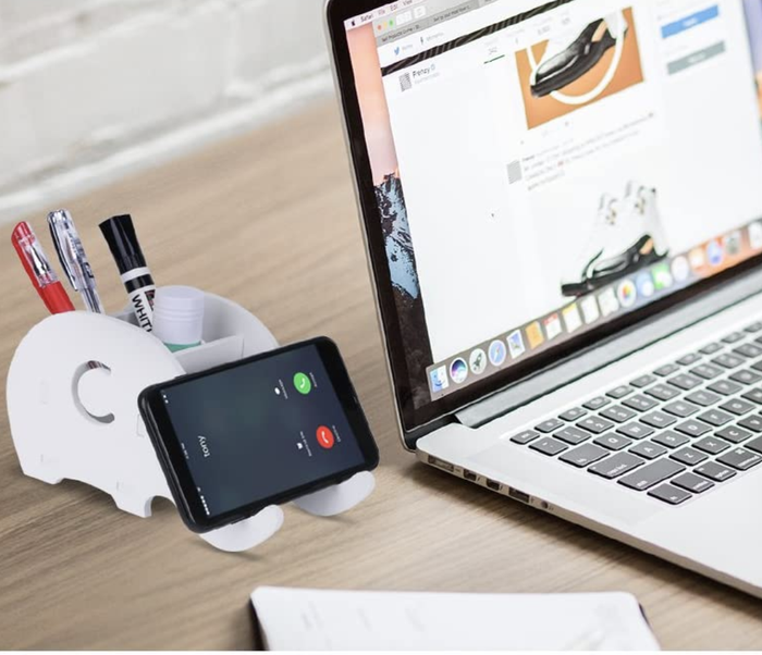 A small elephant-shaped utensil holder, with its 'trunks' cleverly supporting a phone.