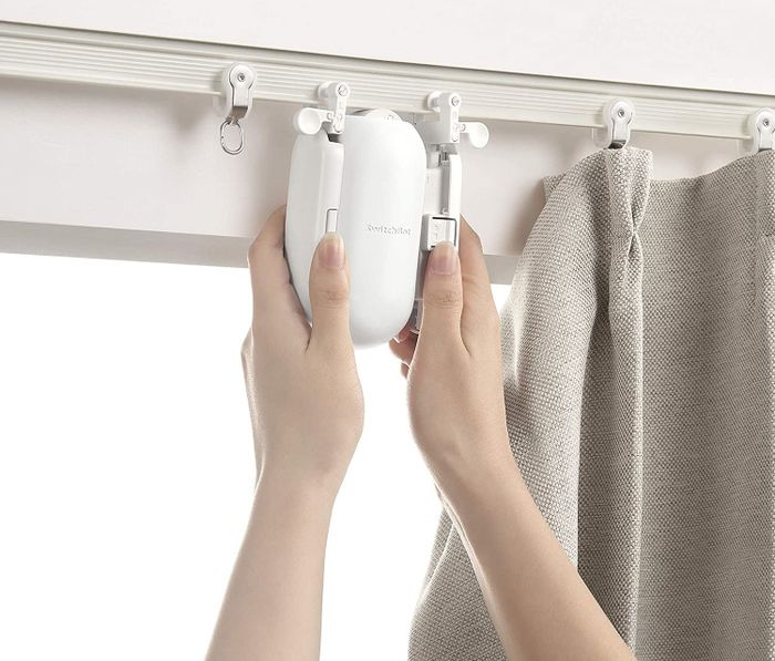 A person attaching the motor to their curtain rod.