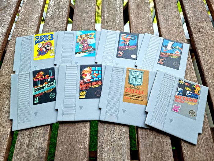 A reviewer's photo featuring eight coasters shaped like classic NES game cartridges, each representing different beloved games.