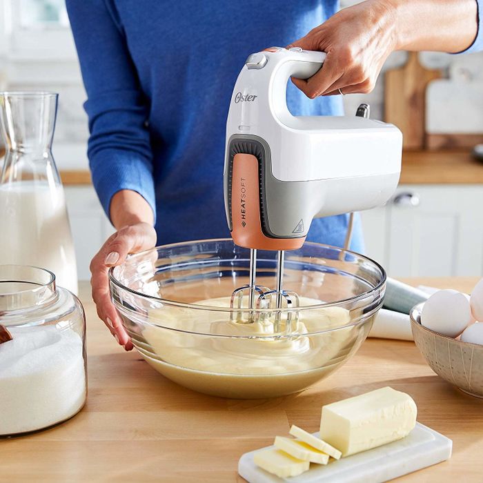 A person operating the Oster HeatSoft Hand Mixer, effortlessly blending ingredients.